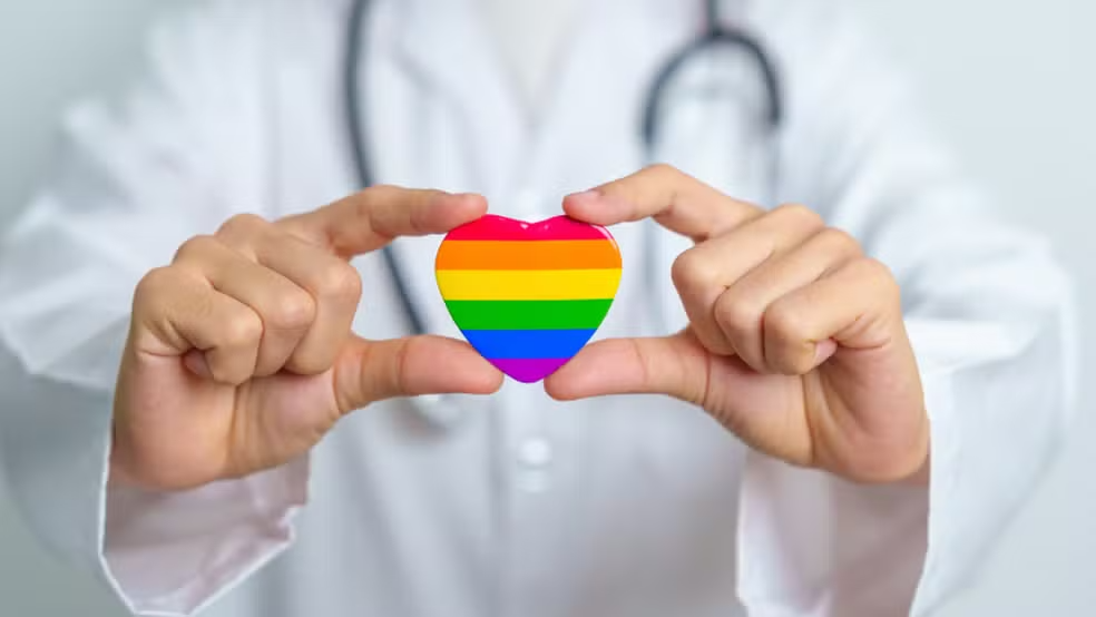 Imagem de um coração com simbolo LGBT sendo segurando por um médico